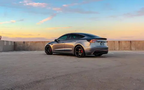 A Quicksilver Tesla Model 3 Performance UP-05 Forged Wheels parked in a parking lot during sunset.