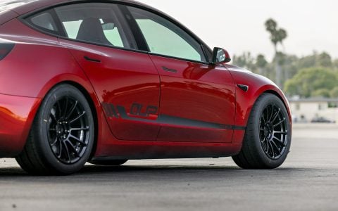 Ultra Red Tesla Model 3 Performance parked on a tarmac, showcasing Unplugged Performance UP-03 Forged Wheels with Yokohama tires and high-performance brake setup.